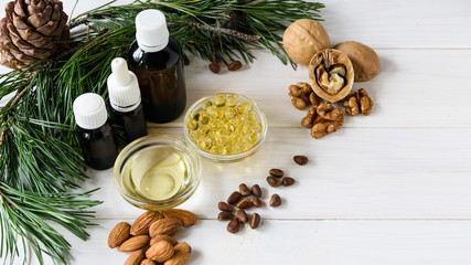 top view natural essential oils of cedar, almond, walnut, on a wok of cedar branches on a light wooden table.