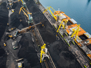 Loading coal anthracite mining in port on cargo tanker ship with crane bucket of train. Aerial top view