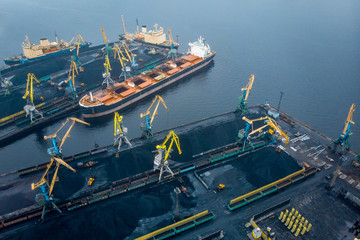 Loading coal anthracite mining in port on cargo tanker ship with crane bucket of train. Aerial top...