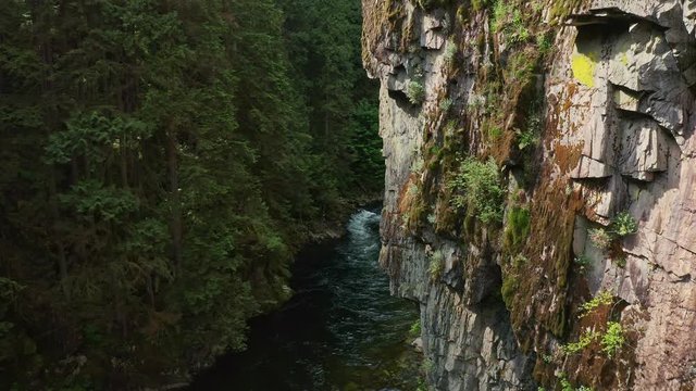 Stunning Drone shot flying close, above the cliff face and and the stream of the Capilano River in Vancouver, British Columbia, Canada
