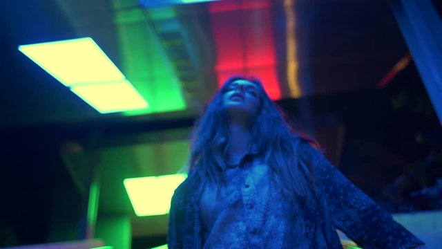 Young woman vaping on an escalator with neon lights