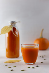Pumpkin juice in glass and bottle on white background.