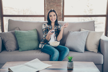 Photo of amazing lady going to watch favorite humor tv show holding remote controller and popcorn plate sitting sofa wearing casual clothes apartment indoors