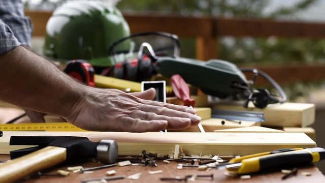 Adult carpenter craftsman takes the measure and with the carpenter's square trace the cutting line on a wooden table. Construction industry, housework do it yourself. Footage.