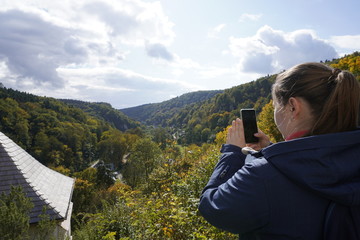 Naklejka premium girl photographs forest mountains, capture the moment, autumn landscape, trees with colored foliage. change of seasons, warm and Sunny autumn