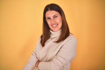 Obraz premium Young beautiful woman smiling happy wearing a sweater over isolated yellow background