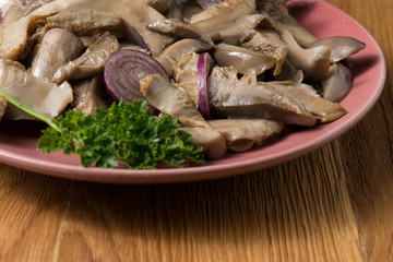 Fried mushrooms on a lilac plate stands on a beautiful wooden background