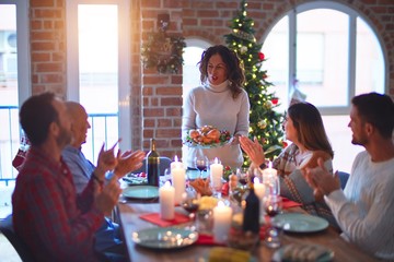 Beautiful family smiling happy and confident. Showing roasted turkey and applauding celebrating Christmas at home