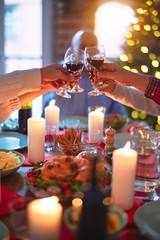 Beautiful family smiling happy and confident. Eating roasted turkey and toasting with cup of wine celebrating Christmas at home