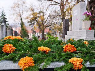 Orange chrysanthemum  flowers and fir tree branches decorate a tomb to the cemetery on All Souls Day. The Day of the Dead is a traditional day to honor the memory of departed relatives.