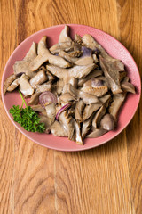 Fried mushrooms on a lilac plate stands on a beautiful wooden background