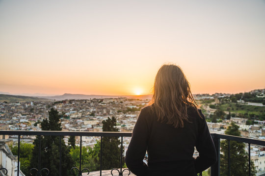 Girl traveler girl watching a beautiful sunrise one morning from the terrace in the top of a building, in Fes, Morocco