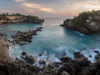 Waves crash on the jagged cliffs in a bay on Nusa Lembongan, Bali, Indonesia