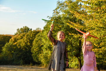 Child pilot aviator with airplane dreams of traveling in summer in nature at sunset children running happily together during beautiful sunny weather in park