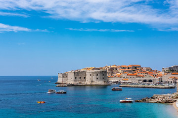 Fototapeta na wymiar Old city walls in historic Dubrovnik city, Dalmatia, Croatia, emerald Adriatic Sea with boats and blue summer sky, popular touristic destination