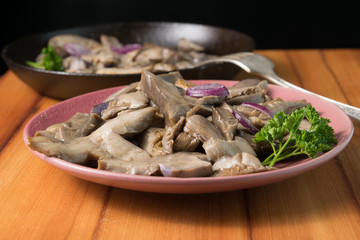 Fried mushrooms on a lilac plate stands on a beautiful wooden background