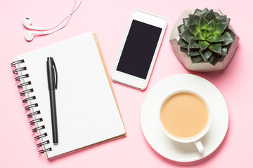 Freelance workplace with notepad, coffee cup, succulent and mouse on pink