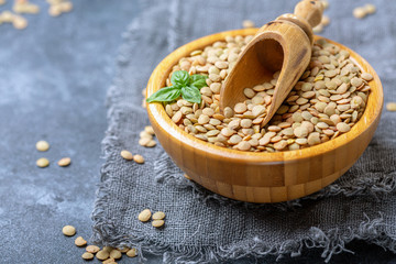 Organic brown lentils and wooden scoop in a bowl.