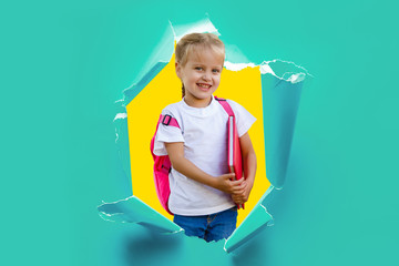 Child girl with book and bag breaking through paper wall.