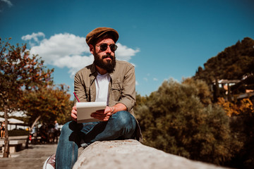 .Young man sitting in the street of Granada, Spain, drawing in his travel notebook. Enjoying the sunset, developing his creativity. Relaxed and carefree. Lifestyle.