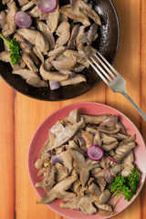 Fried mushrooms on a lilac plate stands on a beautiful wooden background
