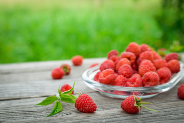  Pink fresh raspberries on an glass vessel on a gray wood background in the garden on the background of green grass Berry Fruit Sadovina Healthy Food hack close up