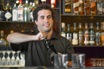 Portrait of caucasian bartender man opens a bottle of whiskey for a hotel bar customer. The concept of service. Focus on the bartender. 