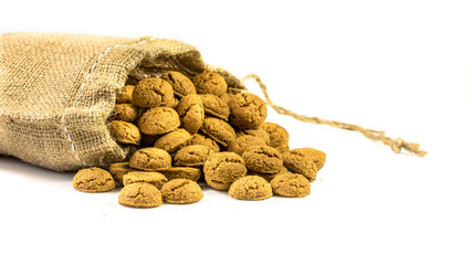 Traditional pepernoten treats in jute bag on white background