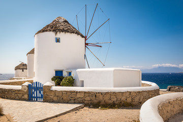 Mykonos, Greece. Scenic view of famous whitewashed windmills in town at the coast on a beautiful summer vacation day. - obrazy, fototapety, plakaty
