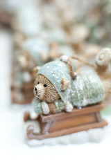 Decorative figurines of a Christmas theme. Statuette of a teddy bear on a wooden sleigh. Christmas tree decoration. Festive decor, warm bokeh lights.
