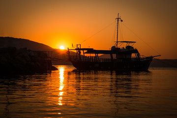 Fototapeta premium The Fisherman preparing for Sailing for fish at sunrise in sea in the morning in Greece. Beautiful sun reflection.
