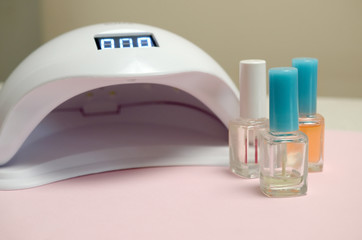UV diode lamp lights for nails and set of cosmetic nail polish for manicure and pedicure on pastel...
