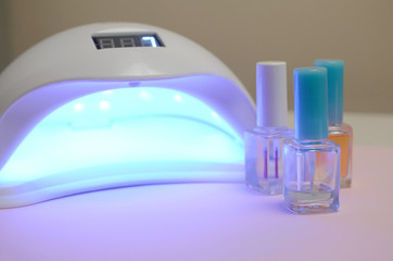 UV diode lamp lights for nails and set of cosmetic nail polish for manicure and pedicure on pastel...