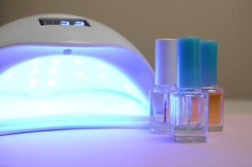 UV diode lamp lights for nails and set of cosmetic nail polish for manicure and pedicure on pastel...