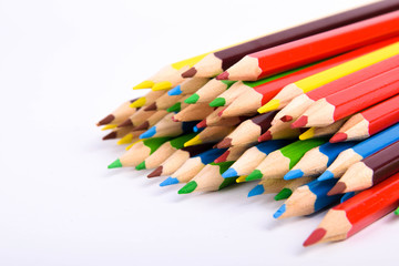 Many different colored pencils on a white background with a place for text and cory space .