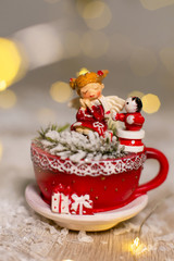 Decoration for Christmas holidays. Warm cozy atmosphere. Statuette of a red mug in which a snowman and a little man sit.