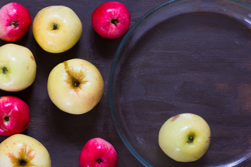 Apples and empty glass dish for baking on wooden background