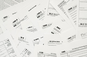 Many tax form blanks lies on table close up. Tax payers paperwork routine and bureaucracy concept