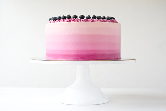 Birthday cake with blueberries and purple gradient cream on white background. Picture for a menu or a confectionery catalog.