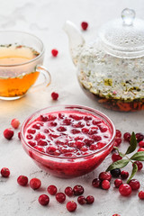 Cranberry jam in a glass bowl and teapot on a white background.