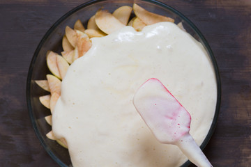 Top view of putting batter on cutting apples before baking on the wooden background