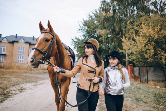 First lessons of horseback riding. Mom and daughter learn to ride a horse.  