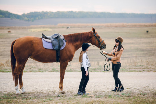 First lessons of horseback riding. Mom and daughter learn to ride a horse.  