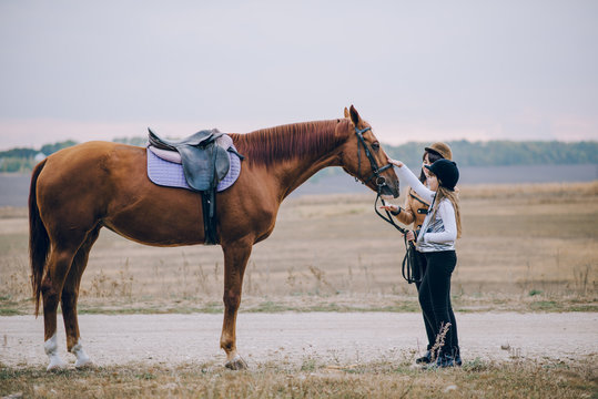 First lessons of horseback riding. Mom and daughter learn to ride a horse.  