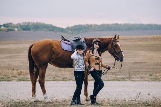 First lessons of horseback riding. Mom and daughter learn to ride a horse.  