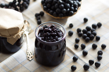 Fototapeta na wymiar Chokeberry jam in jar and chokeberries on the table