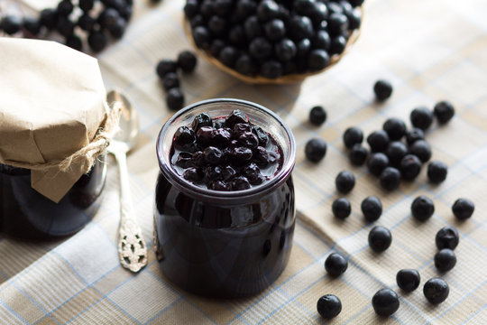 Chokeberry jam in jar and chokeberries on the table
