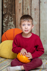 Fototapeta premium a boy in a red sweater with a orange pumpkin