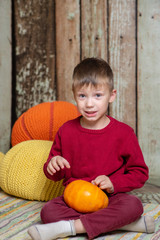 a boy in a red sweater with a orange pumpkin