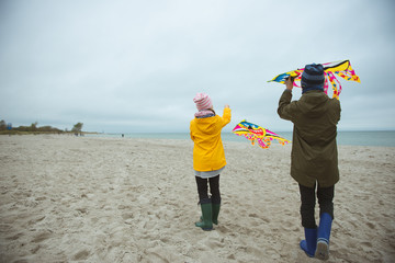 Teen brother and sister playing with kites in sand dunes of Baltic coastline